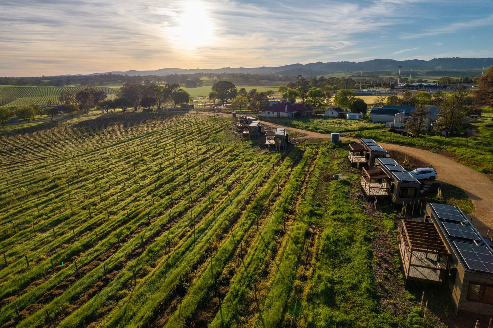 The AUTRA Lyndoch retreats among the Barossa vines at sunset, hills soft on the horizon